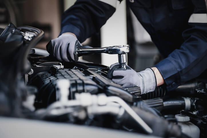 Hands of a mechanic working on a car engine after exploring various auto careers.