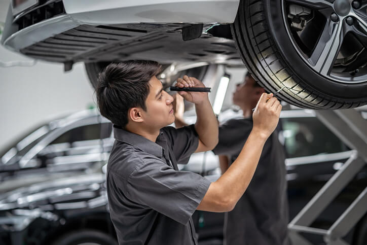 An auto mechanic trainee checking a car’s tires in an automotive school