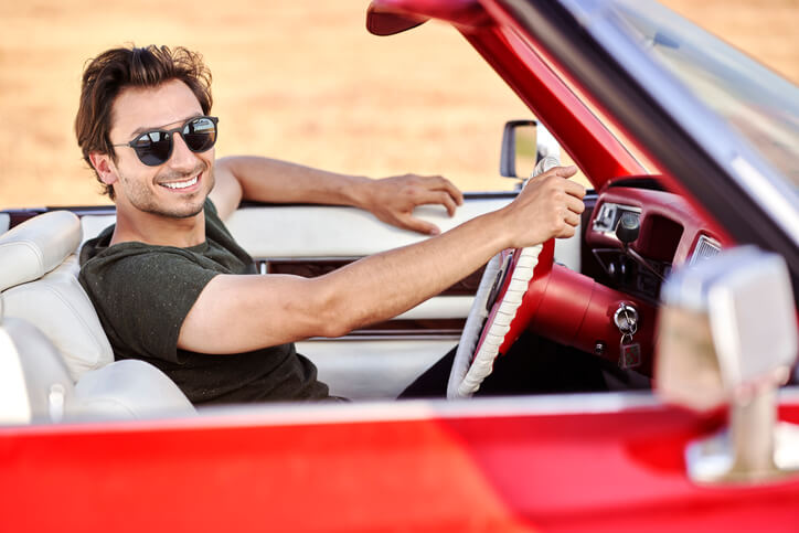 Young male happily driving his car serviced by an automotive school graduate