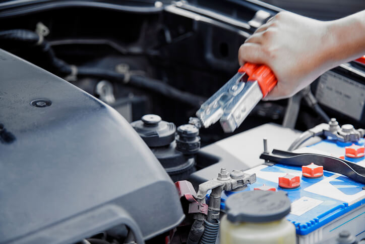 Hybrid and Electrical mechanic training graduate utilising jumper cables on a car battery