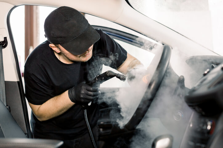 Student in auto detailing training steam cleaning a car