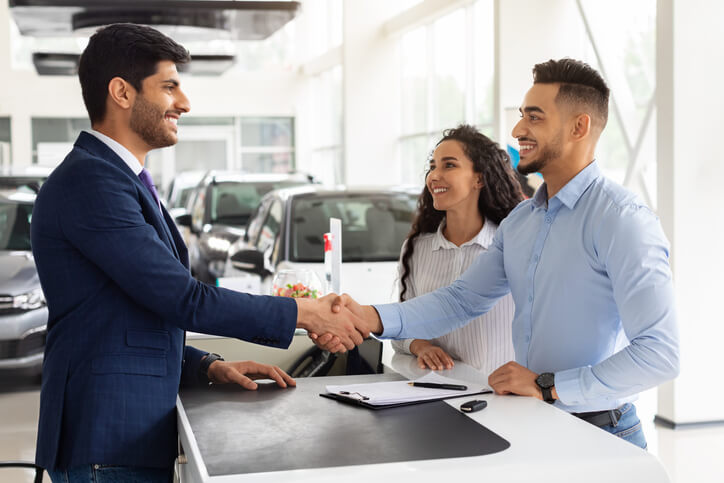Student in automotive sales training greeting clients with a smile