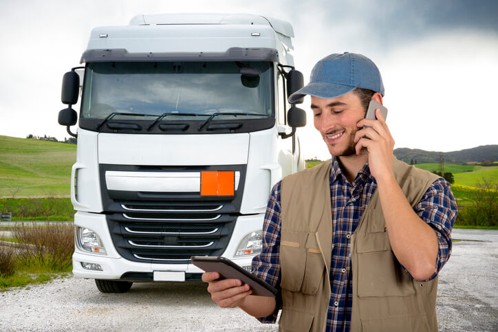 A truck driver holding an electronic logging device after automotive training