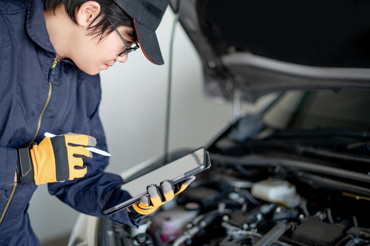 A student in hybrid and electrical mechanic training servicing an EV car