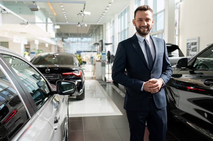 A male car sales professional at a luxury car dealership after automotive school.