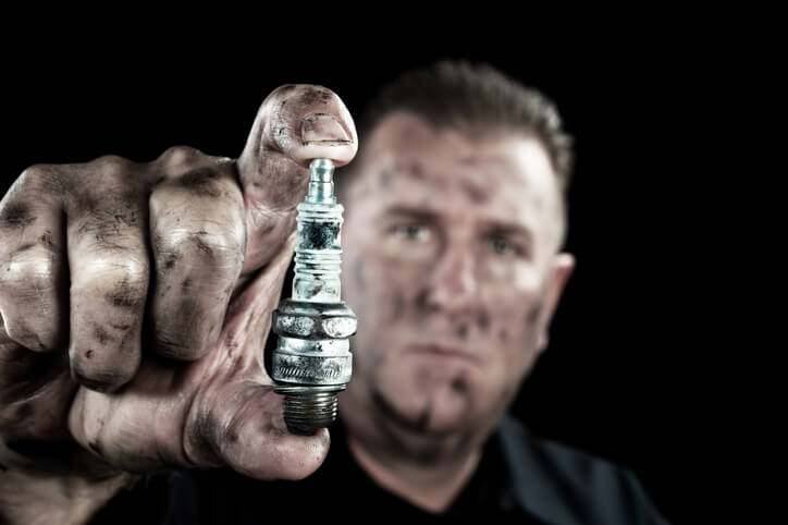 A tune-up technician holding a spark plug after auto mechanic training