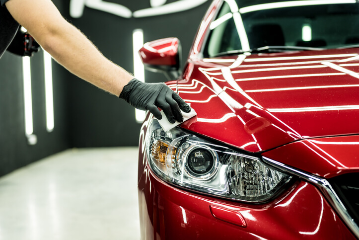 An auto detailer waxing a car using the correct method taught in auto detailing training.