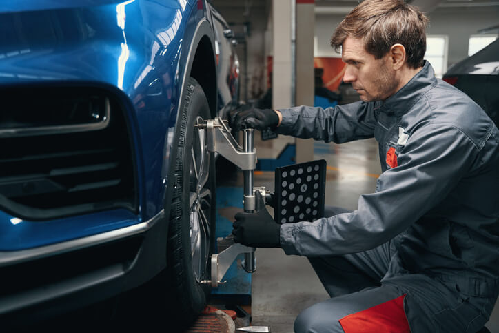 A performance specialist working on the wheel alignment of a high-performance vehicle after automotive technology training.