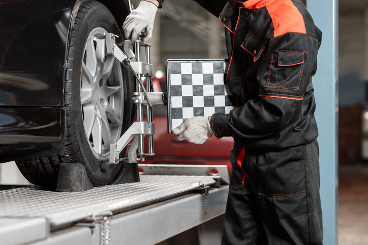 A male auto repair technician performing wheel alignment after auto mechanic training.