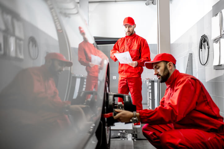 Two auto mechanics working on a vehicle’s alignment in automotive technology training.