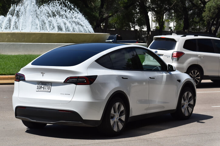 A white Tesla vehicle with brake lights showing, to be explored in hybrid and electrical mechanic training.