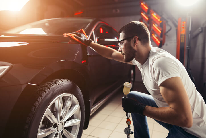 An auto detailer cleaning a car with a cloth