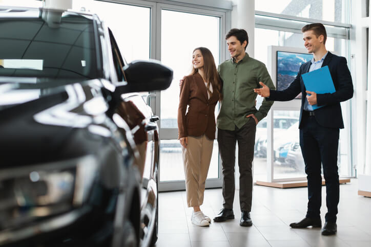 An automotive sales training graduate showing customers a car.