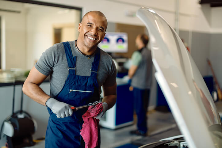A smiling auto mechanic in a body shop after auto mechanic training