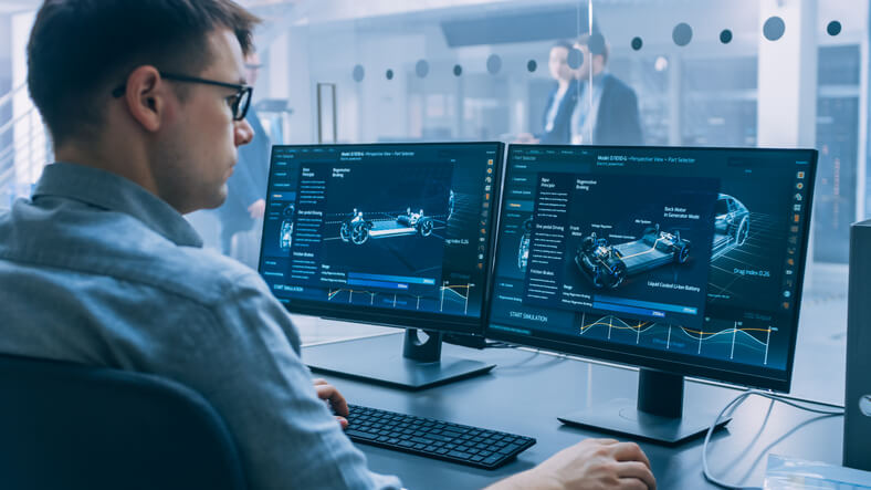 An automotive technology training grad designing a car on a computer.