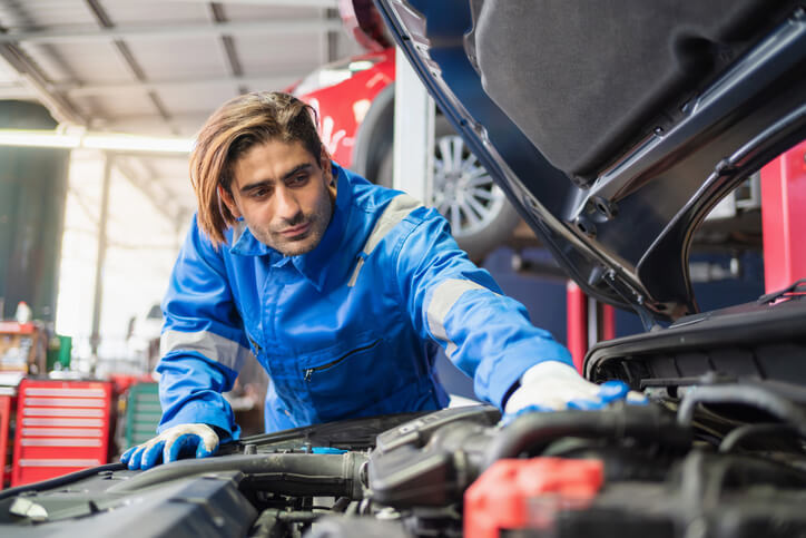 An auto mechanic working on a car engine at the garage.