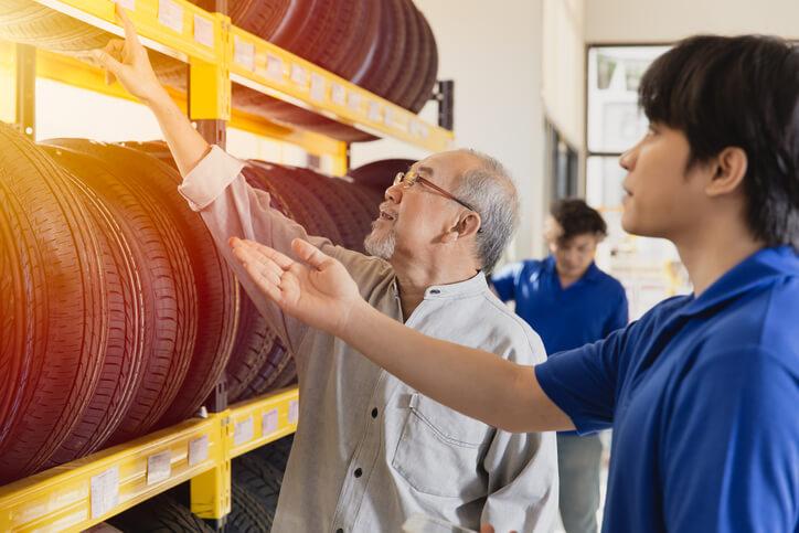 A service advisor training grad helping a customer to find tires.