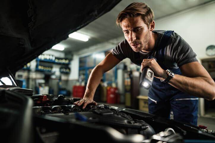 An auto mechanic repairing an electric vehicle after automotive school.