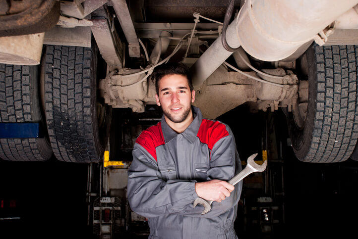 An auto mechanic school graduate posing holding a wrench in a garage