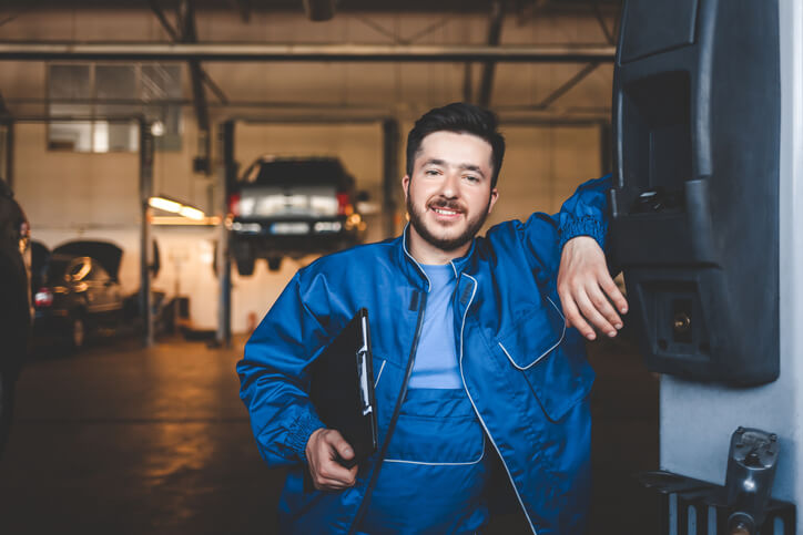 An auto mechanic school training grad posing outside of a garage