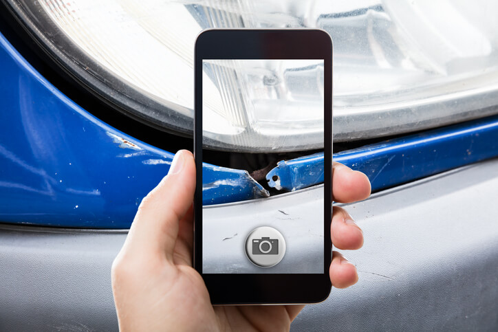 A collision estimator taking a picture of a damaged car after auto repair training