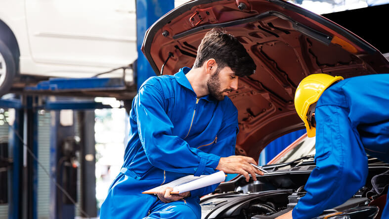 A group of auto mechanics working on a vehicle after completing auto mechanic school