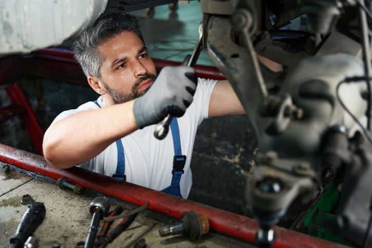 An auto mechanic school graduate working on a vehicle in a garage