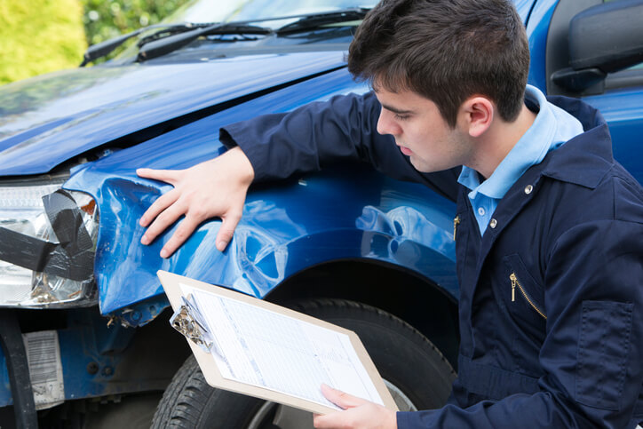 A male collision estimator inspecting a damaged car after auto body estimating training
