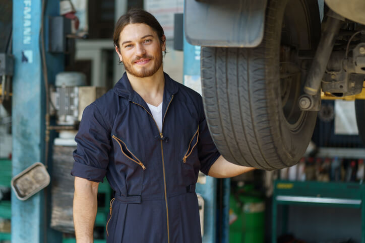 An auto mechanic school graduate posing in a garage