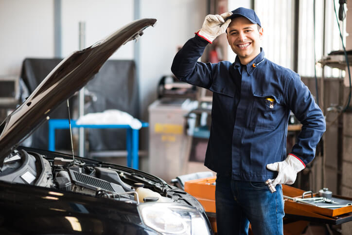 A smiling auto mechanic in a repair shop after automotive training