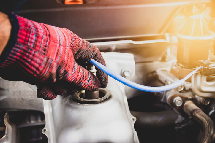 An auto mechanic checking a vehicle’s oxygen sensor after completing automotive service technician training
