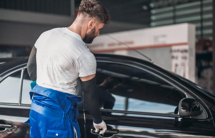 A professional collision estimator checking for hidden rear-end collision damage in a car