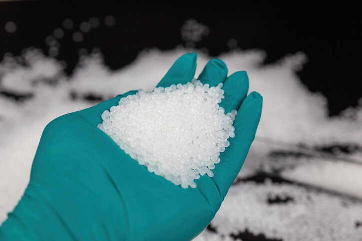A man holding crystallized silicon gel in his gloved hand in an automotive school
