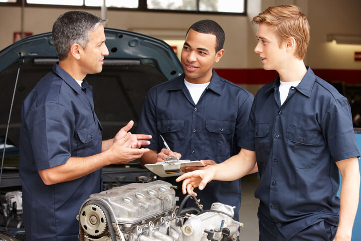 A pair of auto parts training students receiving instruction in a garage setting