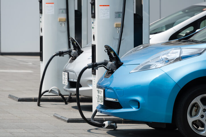 A pair of electric vehicles charging at a charging station as explored in an automotive school