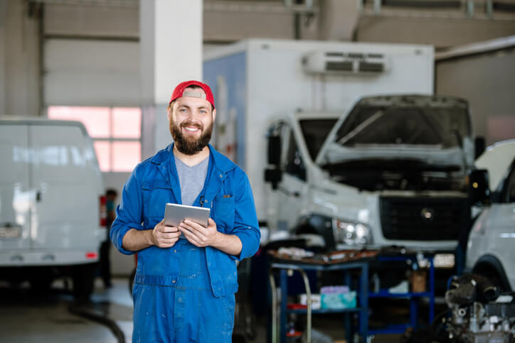 Smiling heavy duty estimator at an auto repair shop after completing his auto parts training