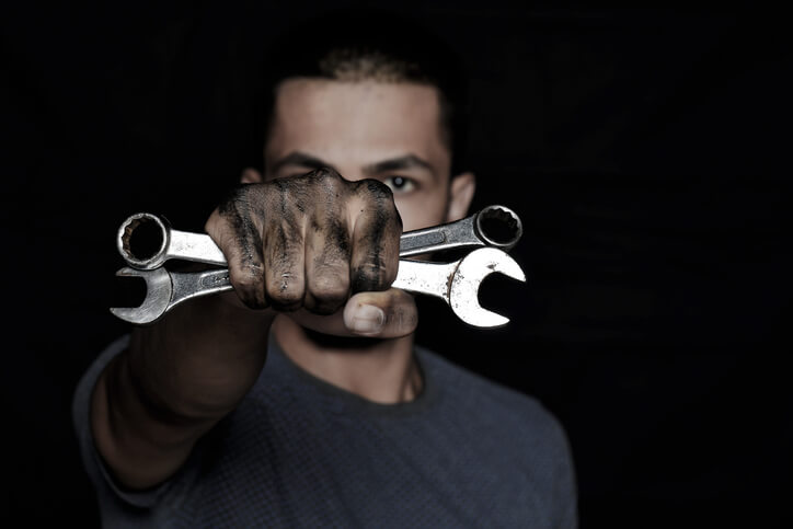 A male auto mechanic holding a wrench
