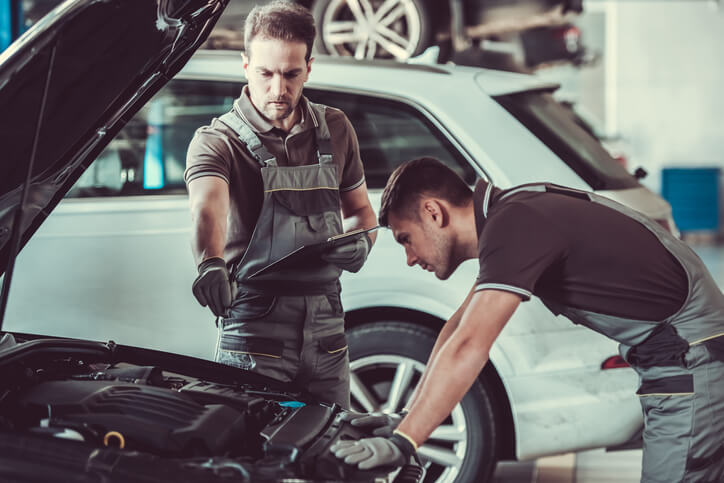 A pair of EV mechanics fixing a common hybrid car problem in a garage