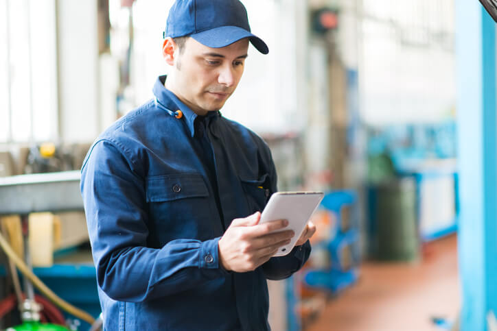 A male auto mechanic checking an auto repair app on his tablet after completing auto mechanic training
