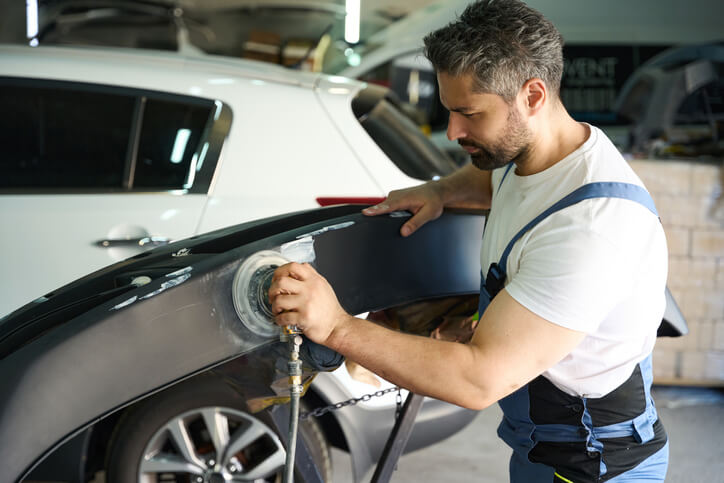 A focused male auto detailing professional buffing an auto body panel
