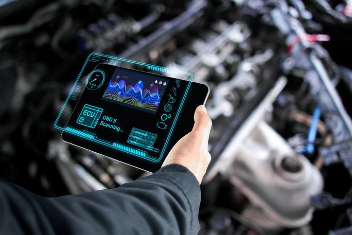 Male auto mechanic checking ECU electronic control unit with OBD or OBD2 wireless scanner tool after completing his hybrid technology training