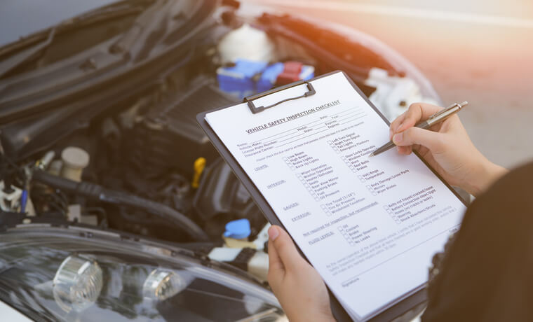 An auto mechanic inspecting a vehicle before a summer road trip