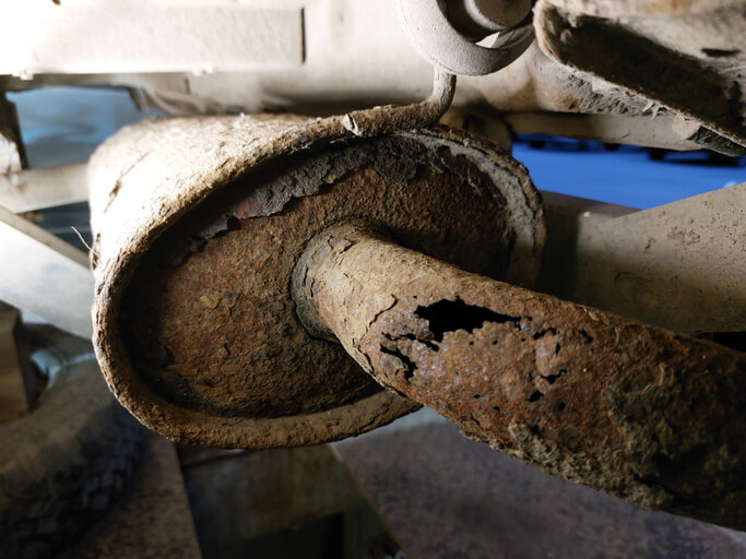 A corroded brake and exhaust parts on a hoisted vehicle