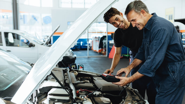 An instructor teaching battery system diagnostics at an auto mechanic school