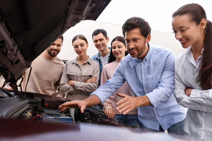 An instructor demonstrating repair accessibility on a modern car model