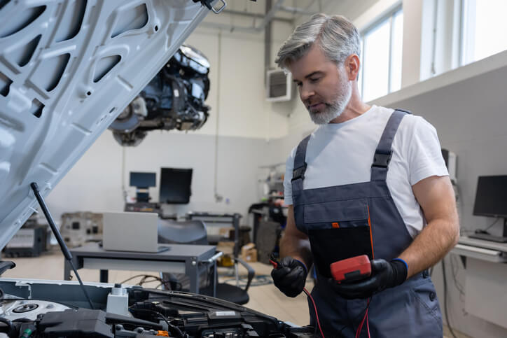 An auto mechanic training student inspecting an MHEV battery system