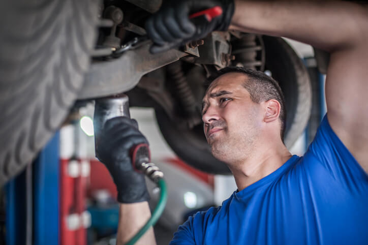 An auto mechanic using computerized alignment equipment