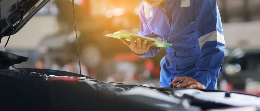 A mechanic using a manual to diagnose a car issue