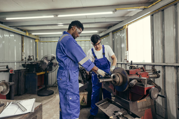 An auto mechanic training student learning how to repair brake issues hands-on