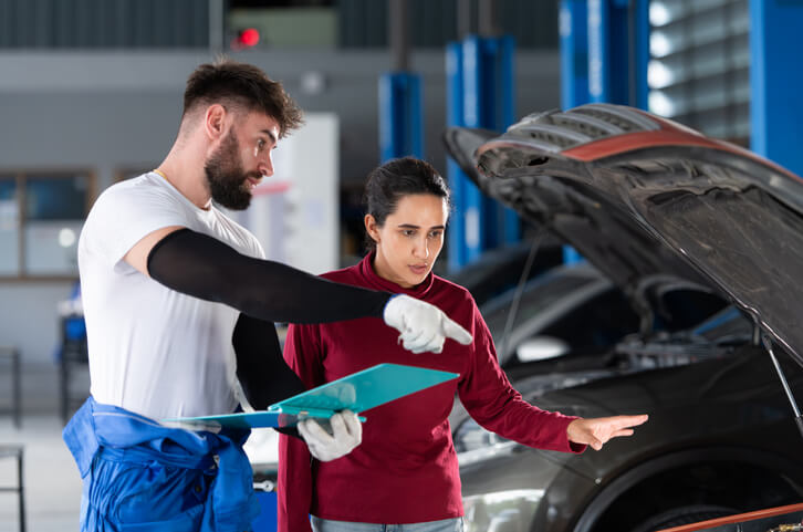 An auto mechanic training graduate explaining a repair to a client